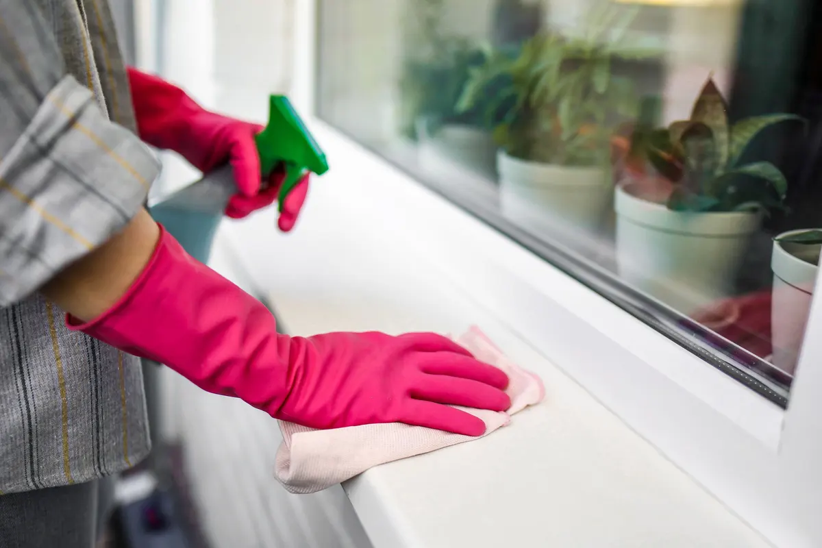 Wiping a windowsill with a cloth